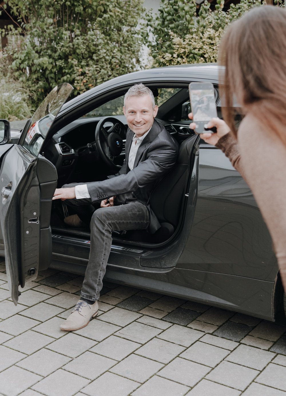 Fotoshooting: Ein Unternehmer im Auto wird mit dem Smartphone fotografiert